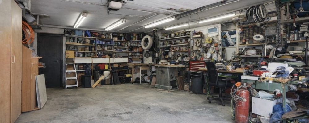 Interiör av ett välutrustat garage med verktygshyllor och arbetsytor.