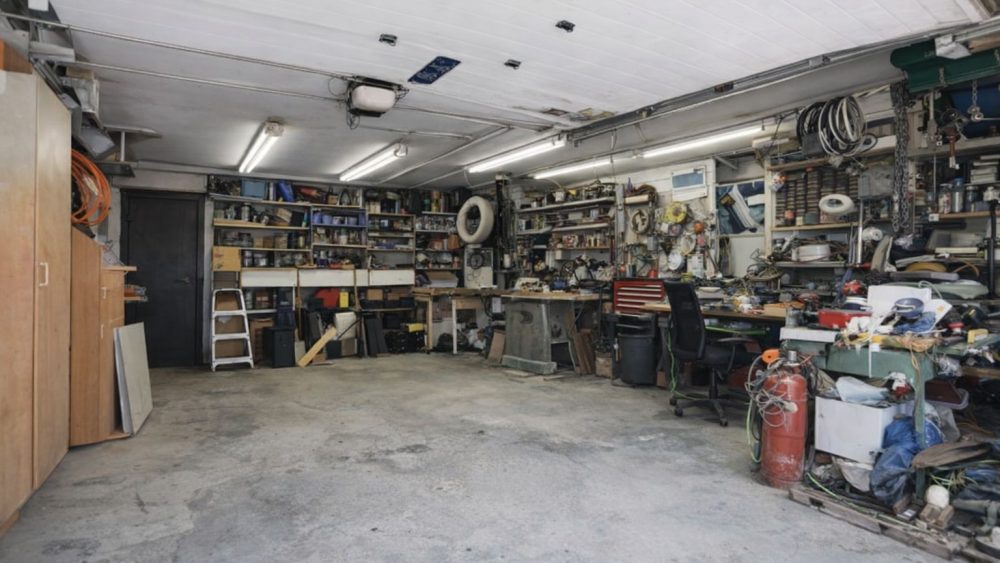 Interiör av ett välutrustat garage med verktygshyllor och arbetsytor.