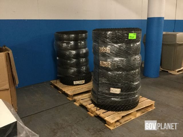 Nya däck staplade på träpallar och omslutna av skyddsplast i ett lager.