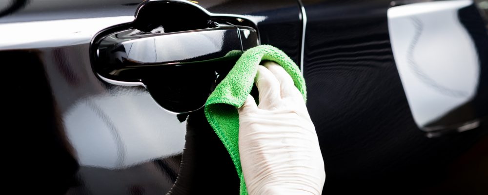 Car detailing series : Worker cleaning black car