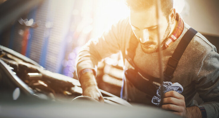 Car mechanic inspecting engine during service procedure.